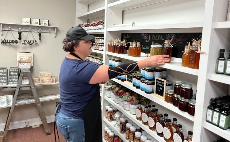 Mandy Hicks organizes her wall of Amish-made jellies and other delights at Mountainside Exchange in Clarkesville. MATTHEW OSBORNE/Staff
