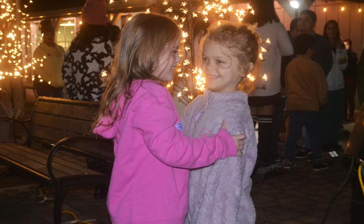 Henlee Jo Wilson and Karli Holcomb embrace one another in the spirit of Christmas at Demorest’s holiday event Wednesday night. BRIAN WELLMEIER/Staff