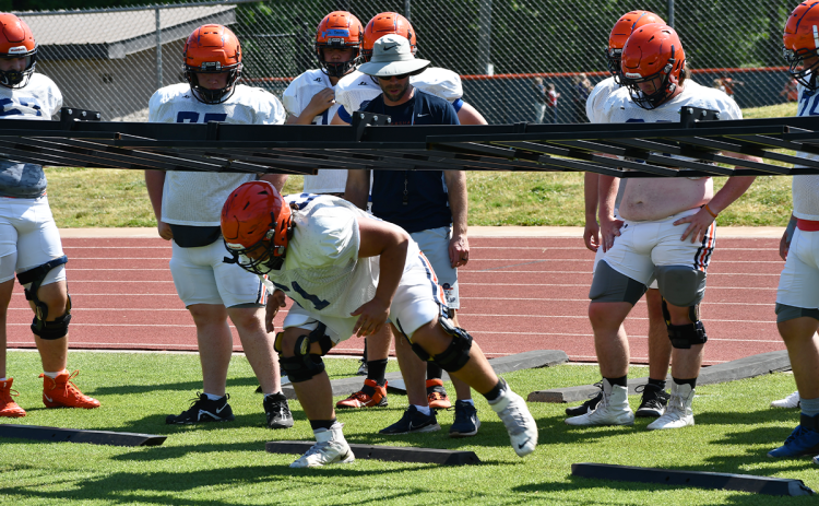 Habersham Central assistant coach Tip Johnson works with linemen Wednesday as rising senior Eddie Jenkins demonstrates proper technique to his teammates. MATTHEW OSBORNE/Staff