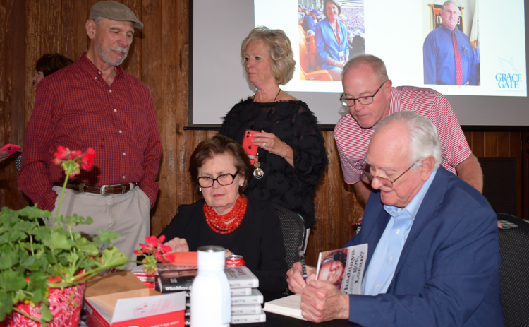 Loran Smith signs copies of his new book while his wife Myrna greets and mingles with fans at the Community House in Cornelia. BRIAN WELLMEIER/Staff
