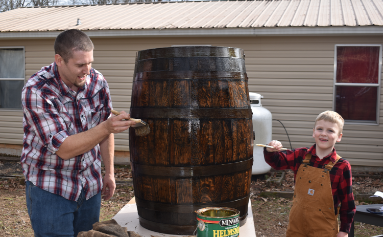 Daniel Rusk and his son Cainan work on one of the barrels that have become a family hobby. BRIAN WELLMEIER/Staff