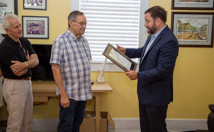 Buck Snyder humbly accepts a plaque from Cornelia Mayor John Borrow as Commissioner Don Bagwell (left) looks on at a ceremony Saturday morning. PETER MADRUGA/Submitted