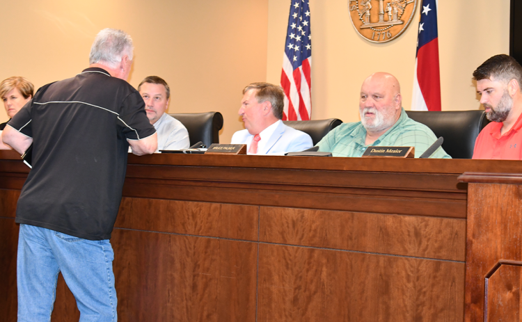 Larry Shedd of Clarkesville (back turned) consults with Commissioners Ty Akins and Bruce Harkness after Monday’s public hearing about the millage rate. MATTHEW OSBORNE/Staff