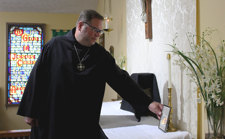 Father Damien Trudeau prepares the altar to host a funeral mass at St. Thomas Anglican Church in Alto. AMARIS E. RODRIGUEZ/Staff