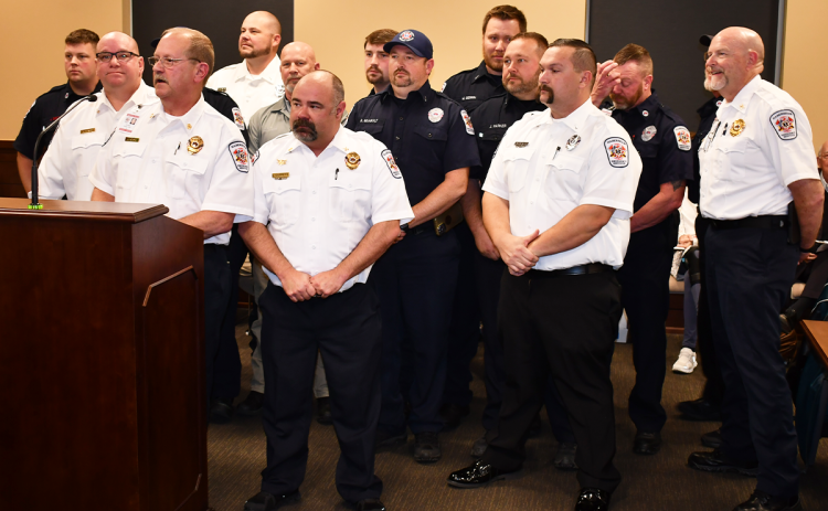 Habersham County Emergency Service employees (from left) Jeff Brown, Jason Davey, Chief Jeff Adams, Jason Garrett, Brad Davidson, Ronnie Davis, Bryan Nix, Randi Seabolt, Mark Gerrin, Jeff Parker, Mack Palmer, Jamie Tyler, Royce Eller and Bill Ramsey stand up in solidarity at Thursday’s special called meeting of the Habersham County Board of Commissioners. MATTHEW OSBORNE/Staff