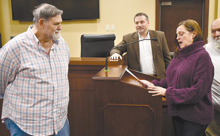 David Barrs (left) listens to a heartfelt speech by colleague Laurie Church at Monday’s county commission meeting as Commissioner Ty Akins looks on.
