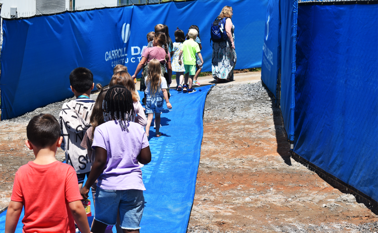 Mrs. Denise Rogers’ first grade class walks through the construction tunnel at  Clarkesville Elementary to reach their  playground at recess Wednesday.  The construction work goes on as the kids learn thanks to coordination between school leaders and workers to eliminate disruptions. MATTHEW OSBORNE/Staff