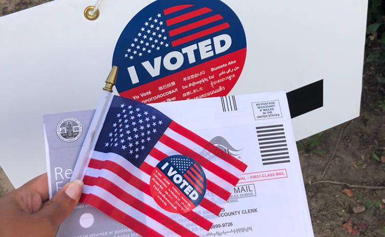 A photo of a voting sticker with a mail advertisement. UNSPLASH PHOTO