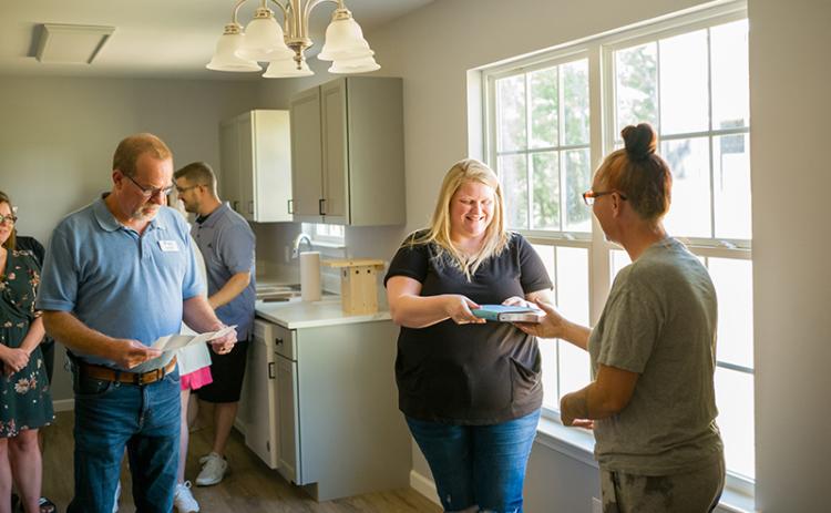 Owner of the most recent Habitat for Humanity home, Lisa Thomas (right), presents Jennifer Payne (center) a Bible and well wishes for her new home. ZACH TAYLOR/Special