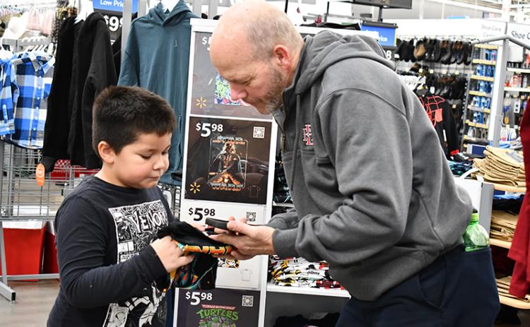 First grader Zayden Tomas Wade picks out a Star Wars T-shirt with Baldwin Fire Chief Joe Roy, organizer of Shop with a Hero. JULIANNE AKERS/Staff