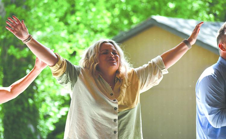 Kayla Ginn raises her hands during a gathering in Demorest. JULIANNE AKERS/Staff