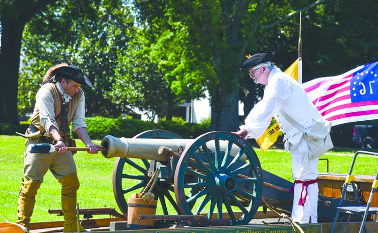 David Louden (left) and Ed Hendricks, dressed in Revolutionary War regalia, service a Revolutionary artillery cannon after it was set off at a Flag Day ceremony to honor Old Glory. JULIANNE AKERS/Staff