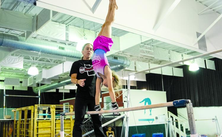 Remmi Raley gets spotted during a bar routine by Coach Jessica Rockwell at Thursday’s practice. ZACH TAYLOR/Special