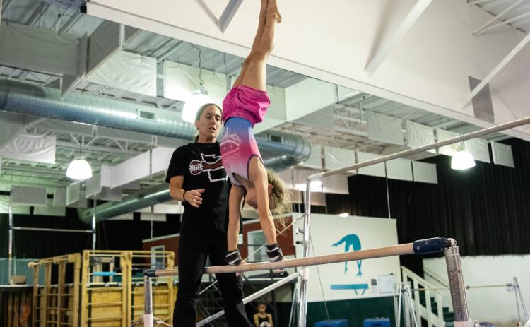 Remmi Raley gets spotted during a bar routine by Coach Jessica Rockwell at Thursday’s practice. ZACH TAYLOR/Special