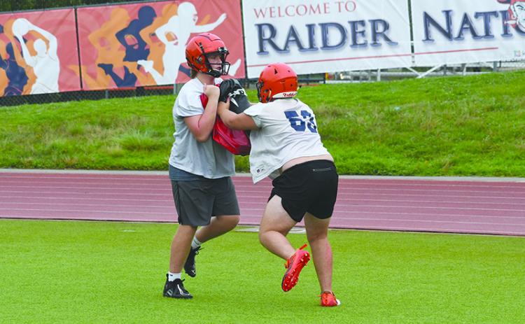 Landon Holbrook holds the bag while Dawson Barnett blocks at practice Thursday morning. LANG STOREY/Staff