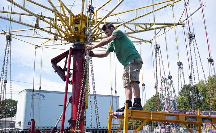 Tim McCoy adjusts the chains on the swing ride before testing its functionality. ZACH TAYLOR/Staff