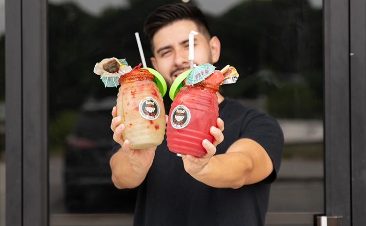 Luis Covarrubias holds at Raspas El Tigre a watermelon agua fresca and cucumber-lime agua fresca topped with ice cream and candy. ZACH TAYLOR/Staff