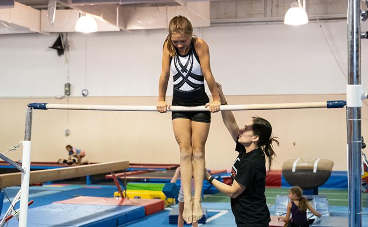 Coach Jessica Rockwell helps out one of her athletes on the bars. ZACH TAYLOR/Staff