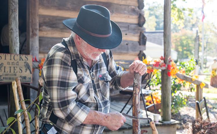 Jeff Blackwell carves into a cane during Clarkesville History Harvest on Saturday. His passion is woodworking, which he says brings him peace. ZACH TAYLOR/Staff