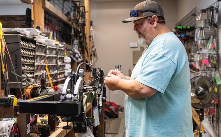 Greg Hope tunes a new bow in a bow press for a customer during a workday on Wednesday. Hope is one of two brothers who manage the archery, gun and shooting range business in Demorest. ZACH TAYLOR/Staff