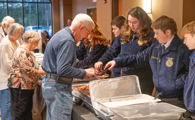 Farm Bureau Board Member Danny Brooks is served a hot meal from Crossroads Cafe by Habersham County FFA’s Aydan Savage. ZACH TAYLOR/Staff