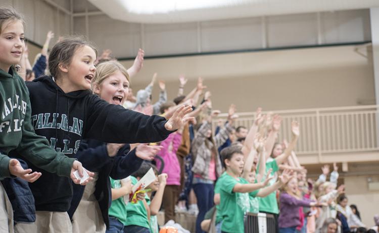 TFS Students Allegra Perry, Piper Prince and Riley McCracken cheer on the Piedmont Lions and reach to catch pom-poms and bouncy balls given away at the game. JULIANNE AKERS/Staff