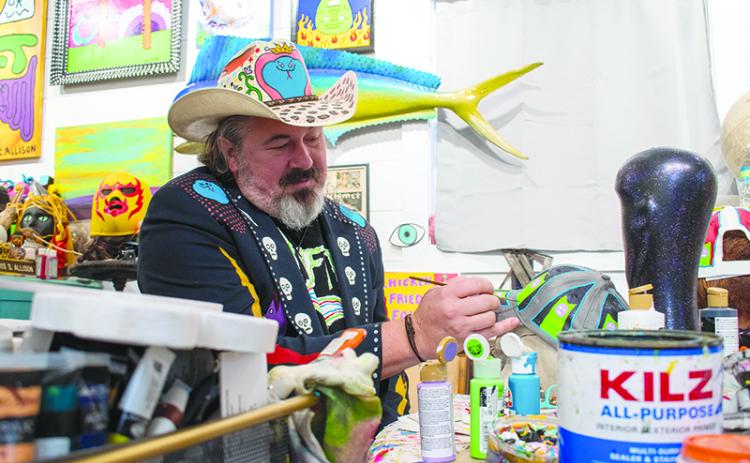 Chris Allison paints a hat at his art studio in Mt. Airy. JULIANNE AKERS/Staff