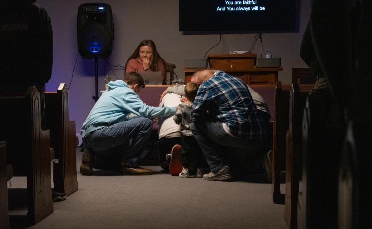 Some men of the church come before the altar to pray, and their fellow church goers follow to lay hands in support.  HANNAH CAUDELL/Staff