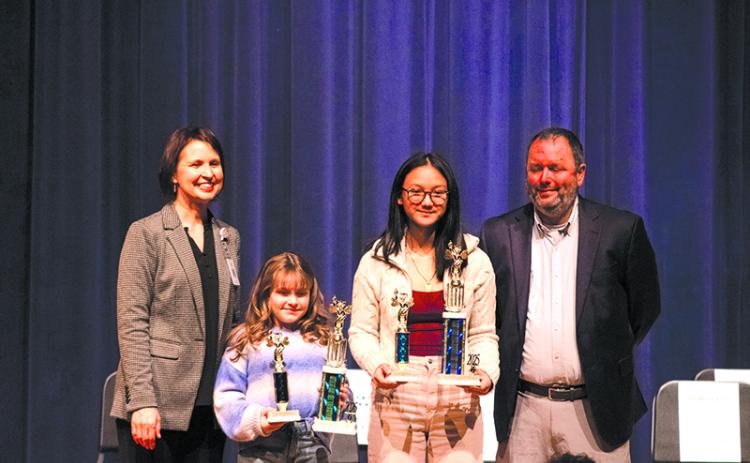 From left, Director of Elementary Schools Dr. Susan Davis,  Woodville Elementary School student Wiley Colston, Hilliard A. Wilbanks Middle School student Khamla Laosalie, and  Assistant School Superintendent Patrick Franklin stand on the stage after the Habersham County School System spelling bee competition for photos. Laosalie won first prize after multiple rounds, and Colston earned the runner-up spot. HANNAH CAUDELL/Staff