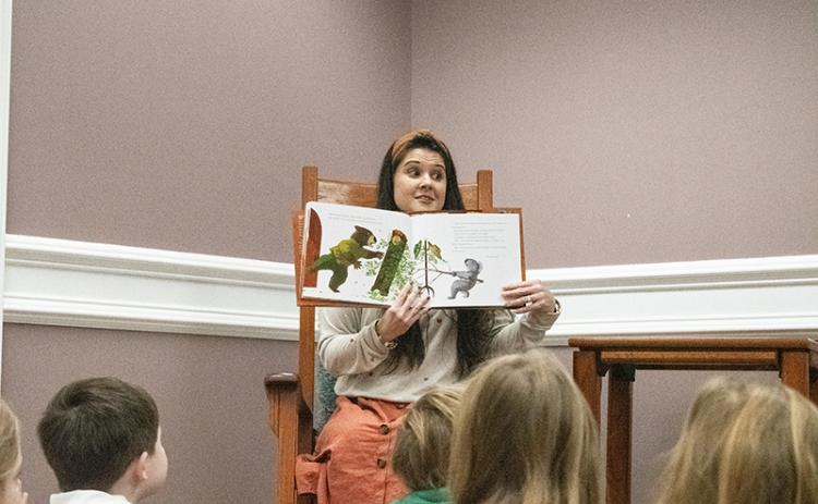 Amanda Almazan, the Clarkesville Library’s youth services coordinator, takes a seat in the rocking chair amongst the children sitting at her feet to read this year’s pick for the featured title, Wombat Said Come In by Carmen Agra Deedy. HANNAH CAUDELL/Staff