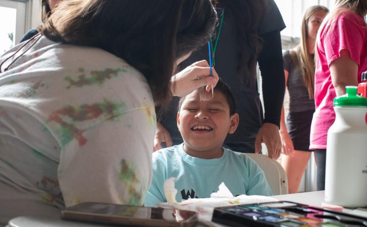 Mateo Mateo-Diego gets into the Lion Pride spirit while a volunteer paints his face to resemble the cat’s signature mane. HANNAH CAUDELL/Staff