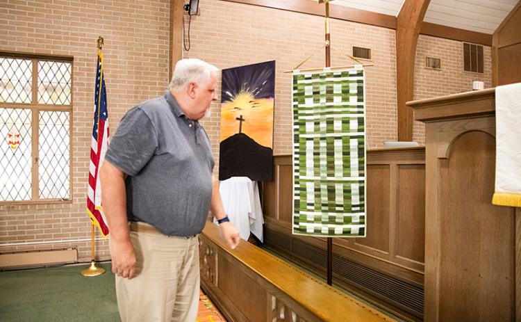 Pastor Randy Kanipe shows the weaving banner in the sanctuary. The weaving banner is a display of more than 130 pieces of fabric brought by an individual from the now mixed congregation, showcasing unity as one church body. ZACH TAYLOR/Staff