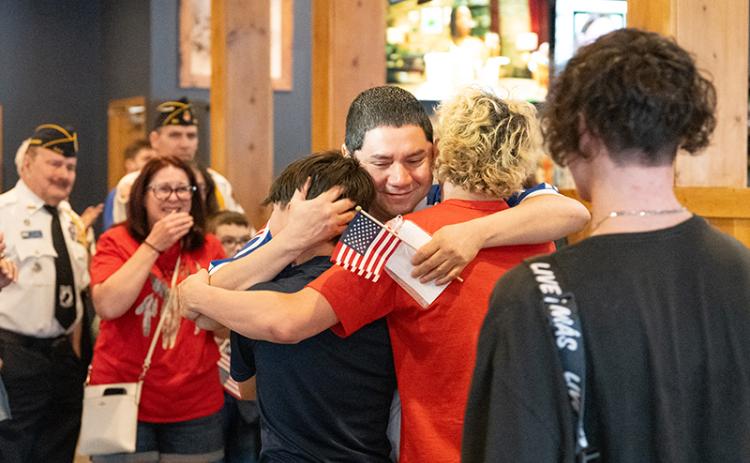 CWO-3 Jose Saravia hugs his sons, Eli Saravia, Christian Saravia and Gabe Lorenzo after surprising them at Bigg Daddy’s in Cornelia after being deployed for more than seven months. ZACH TAYLOR/Staff