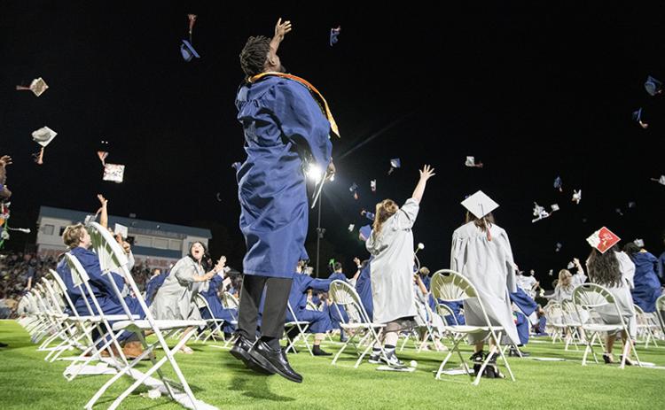 Kendall Respress leaps into the air as he throws his graduation cap with other graduates. ZACH TAYLOR/Staff