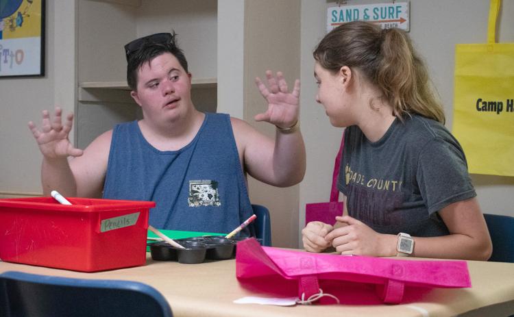 Ethan Little (left) describes his vision to Camp Counselor Ella Ballard during arts and crafts on Wednesday. The campers decorated picture frames, which will house a photo of them with their counselor at the end of camp on Sunday. (HANNAH CAUDELL/Staff)
