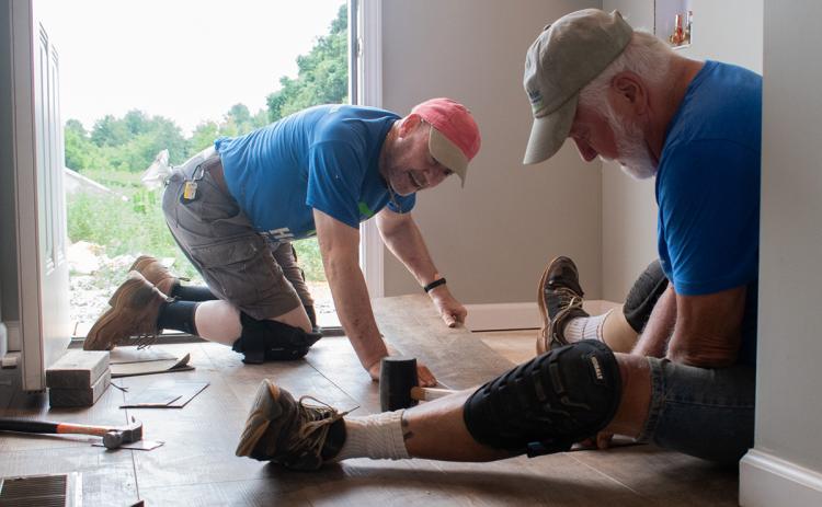 From left, Todd Valentini and Richard Price help each other put flooring in at House 81, one of the few homes Habitat for Humanity is building on the same property. (Hannah Caudell/Staff)