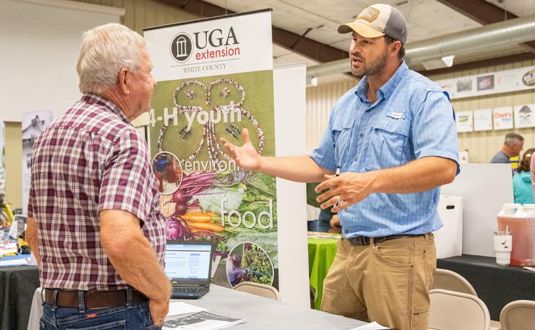 Nathan Eason (right) speaks with a farmer at the North Georgia Ag Expo about the things the UGA Extension does for the state’s agricultural interests, including education. (Zach Taylor/Staff)