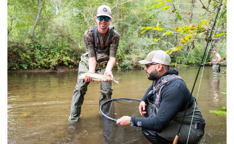Jackson Savage holds a fish after being guided by Seth Underwood during the fly fishing festival on Sunday. (Zach Taylor/Staff)