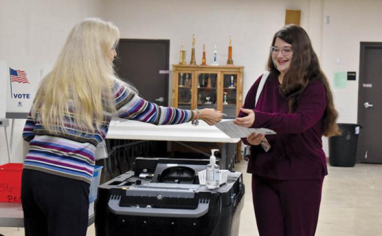 Demorest Precinct Poll Worker Sonya Frady hands Megan Zimmerman a voter sticker after voting Tuesday morning. (Samantha Sinclair/Staff)