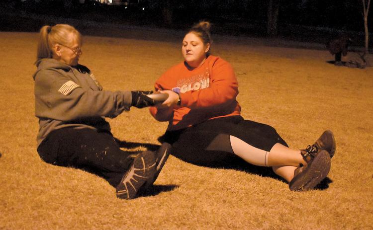 Janice “Buttercup” Gilbert and Brittany Washington pass a weight at one workout station. (Samantha Sinclair/Staff)