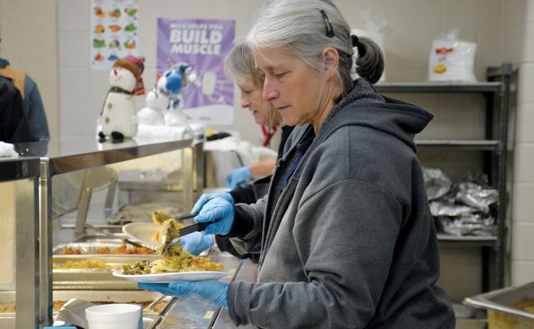 Food Factory’s Lisa Short scoops food on a plate for a lineman Wednesday night. (Samantha Sinclair/Staff)