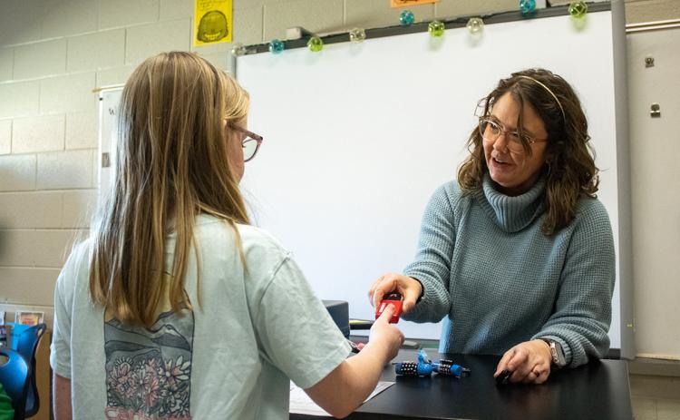 Discovery Teacher Hannah DeMore hands a lock to one of her students, who wishes to see if she broke the code during a class exercise. (Hannah Caudell/Staff)