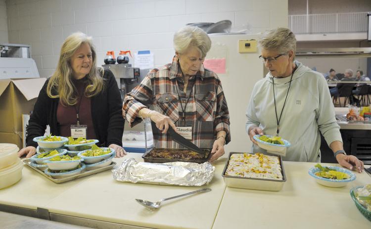Kitchen volunteers Kim Finley, Claudia Jessup and Tina Hatcher prepare meals for the guests at the warming center Monday night. (Samantha Sinclair/Staff)