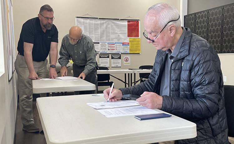 Joey Duncan fills out paperwork to run for reelection for the Habersham County Board of Education District 5 seat while Habersham County Board of Commissioners District 3 candidate Jason Smith talks with Habersham County Republican Party representative Jim Ferraro in the background. (Hannah Caudell/Staff)