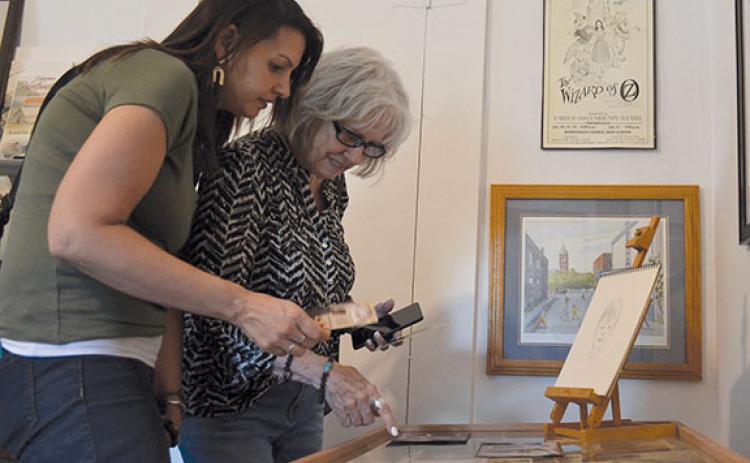 Lisa Urbano and Carma Parrish look at pieces as they read informational cards about John Kollock. (Samantha Sinclair/Staff)