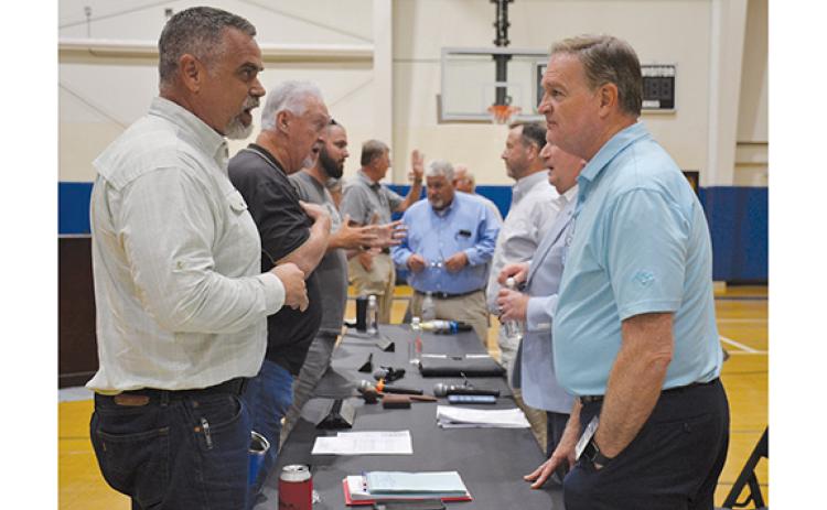 Brett Miller talks with County Manager Tim Sims following the town hall meeting Thursday night as other community members talk with commissioners and county staff in the background. (Samantha Sinclair/Staff)