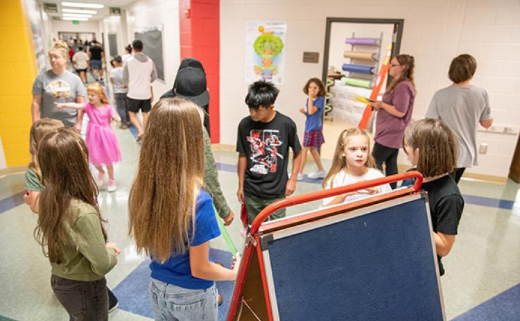 Students and parents refer to a board of names to determine where to meet teachers for the beginning of the school year’s open house last year. (File)