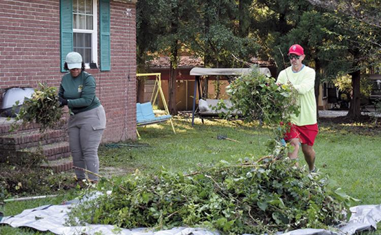 From left, Cristina Simmons and Cornelia City Manager Dee Anderson help clean and pick up trimmed branches at a home in the city during the Helping Hands event on Saturday. (Noah Ansley/Staff)