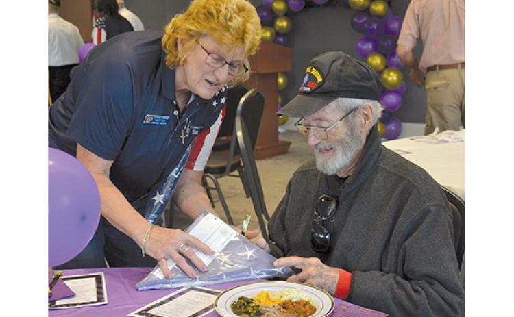 Connie Barrow hands a retired flag to Gene Griffith at the luncheon. Griffith is a U.S. Marine who was wounded in Korea. (Samantha Sinclair/Staff)