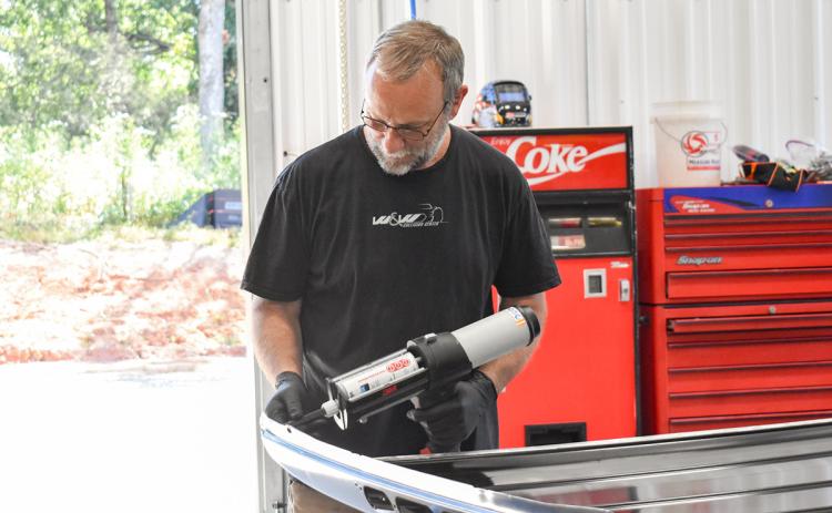 Tommy Dalton, a trainer at W&W Collision Center, prepares to apply glue on the roof of a truck for a repair. (Hannah Caudell/Staff)